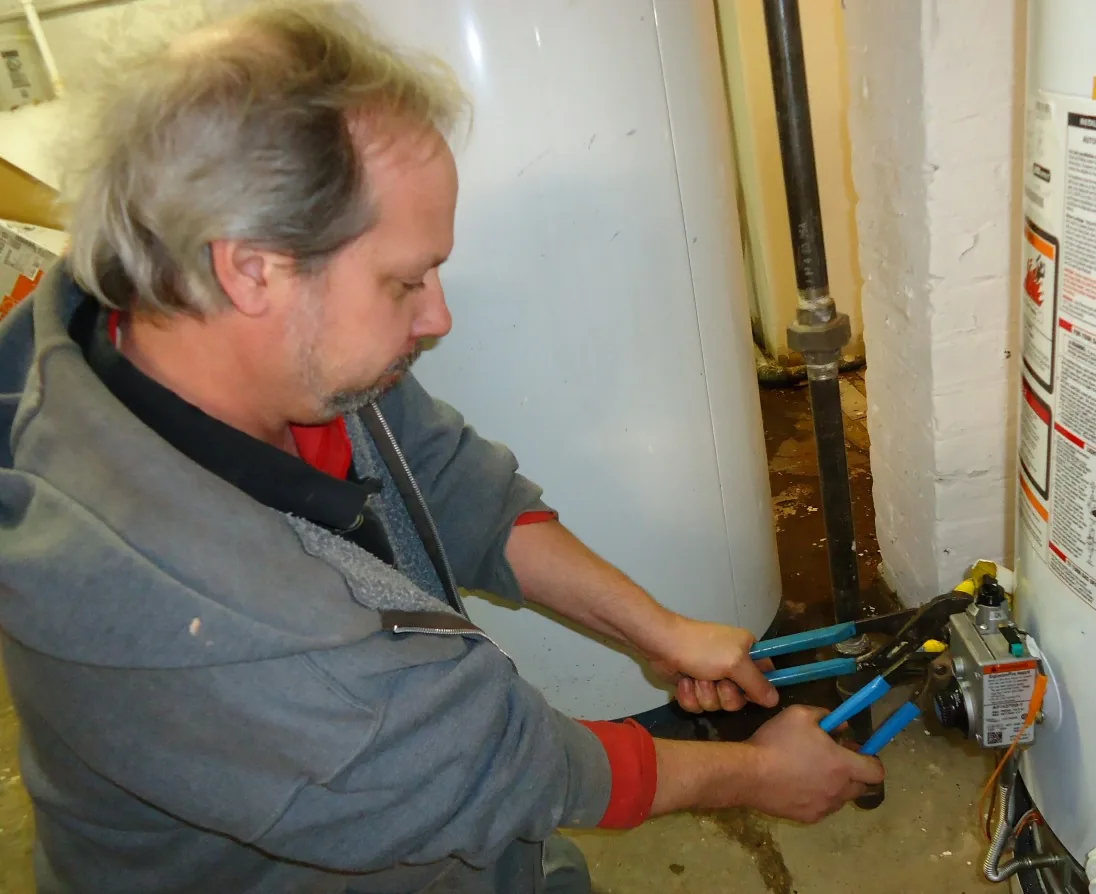 Artisan plombier avec outillage professionnel lors d'une intervention à Tournai